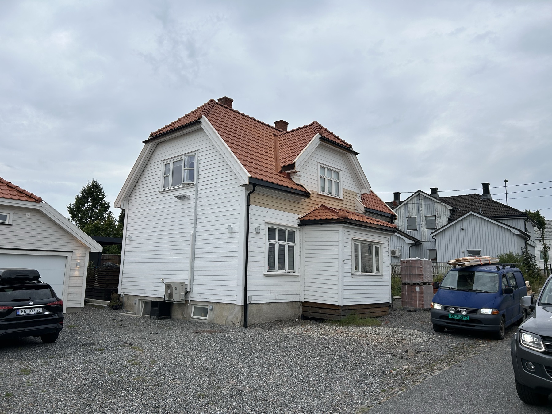 Hvit bolig med ny rød takstein og garasje ved siden av